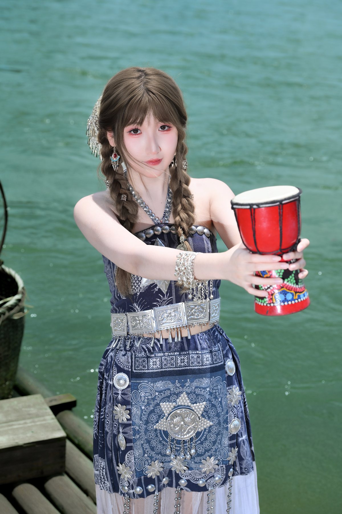 Cici holding a red drum by the water