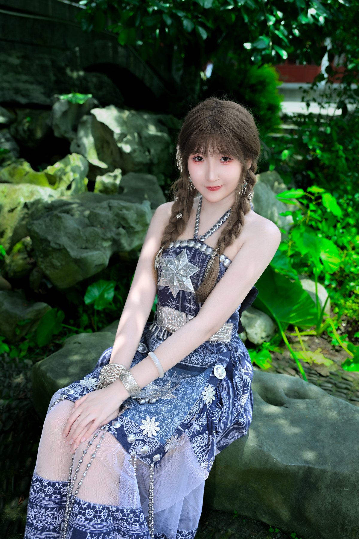 Cici sitting among rocks and green leaves