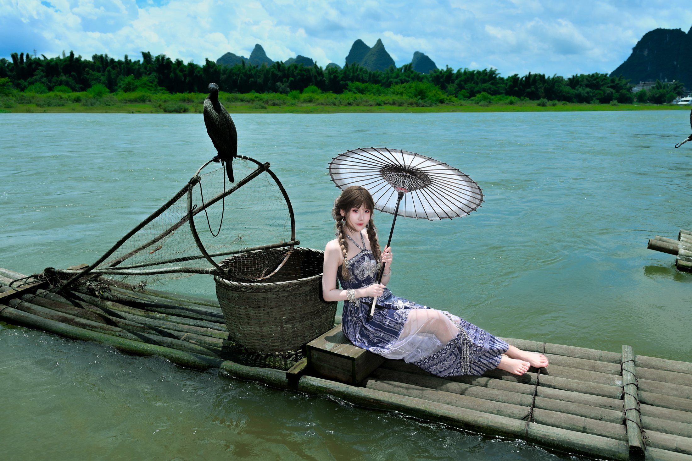 Cici sitting by the river with Guilin mountains behind her
