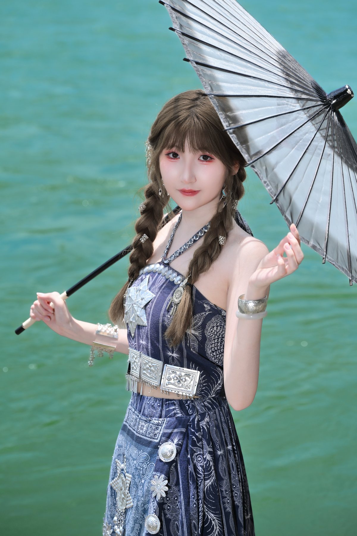 Cici holding a paper umbrella near the river